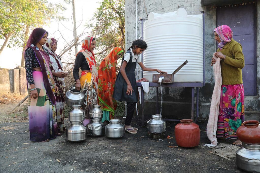 women and girls at a water tank