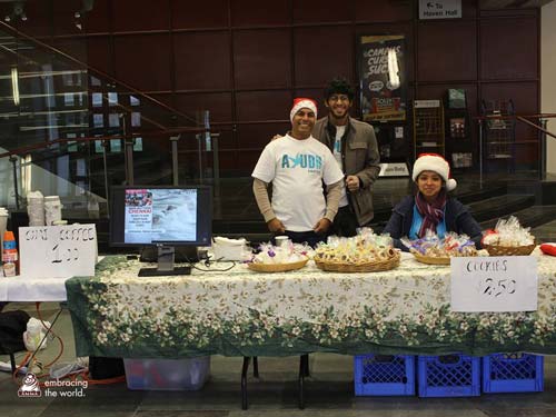 Volunteers stand at table selling cookies and chai