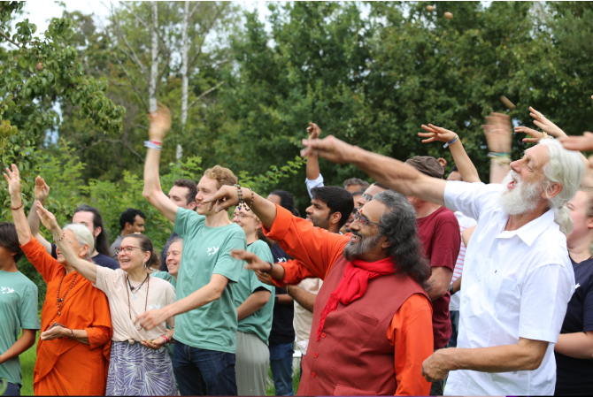 Swamiji and other participants smiling as they throw seed balls 