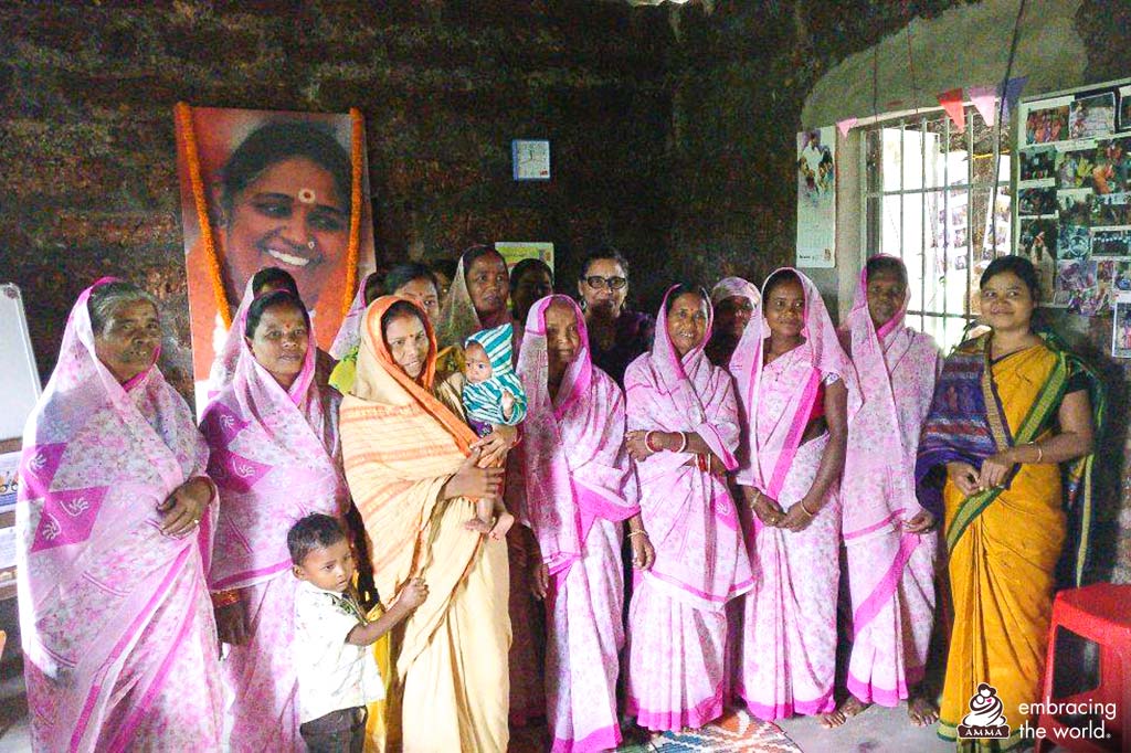 Village women in matching saris stand with UN officer