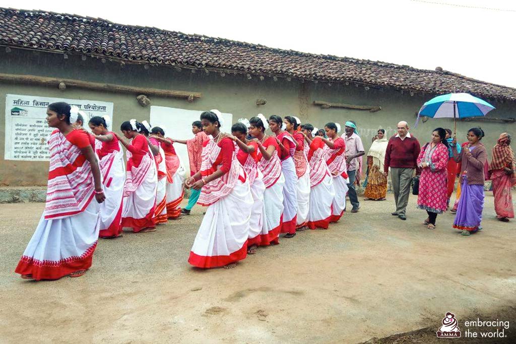 Women dressed in red and white saris perform a traditional dance