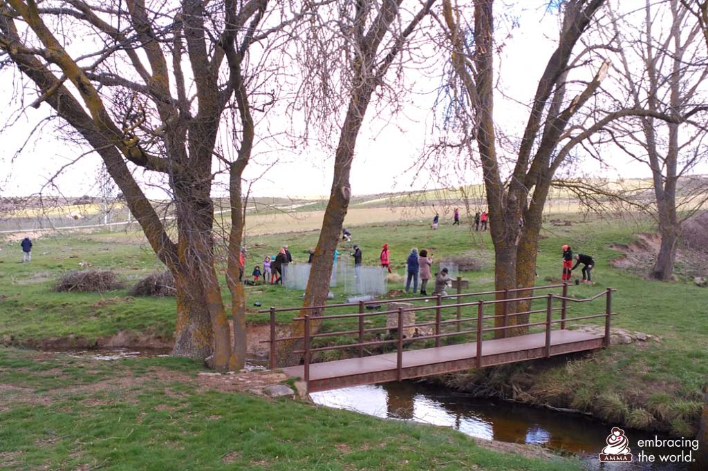 A stream with a bridge next to working volunteers