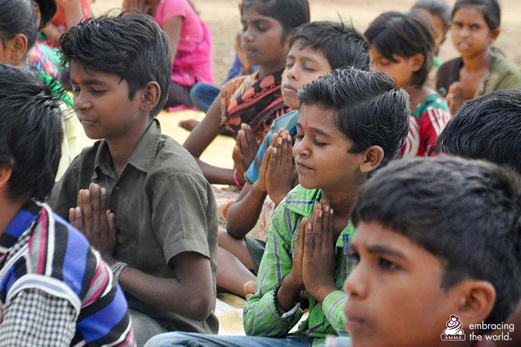 Children sit with their hands in prayer