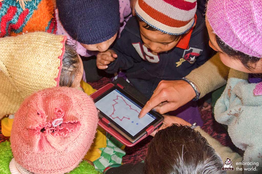 A teacher shows a tablet and children gather to see