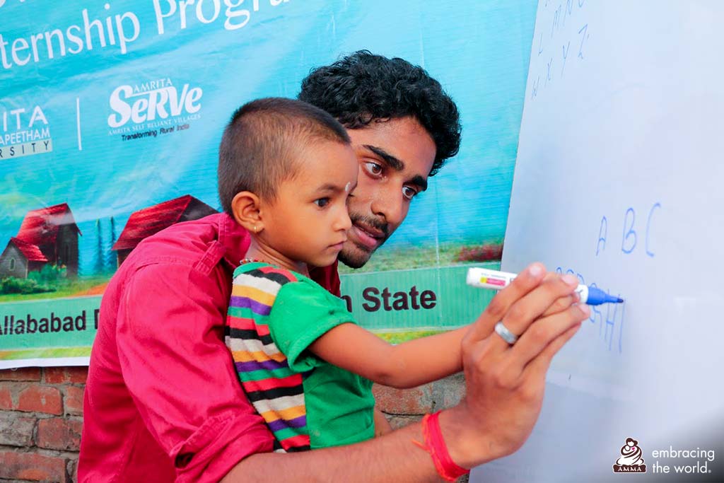 A man holds a small child in his arms as the child draws on a board