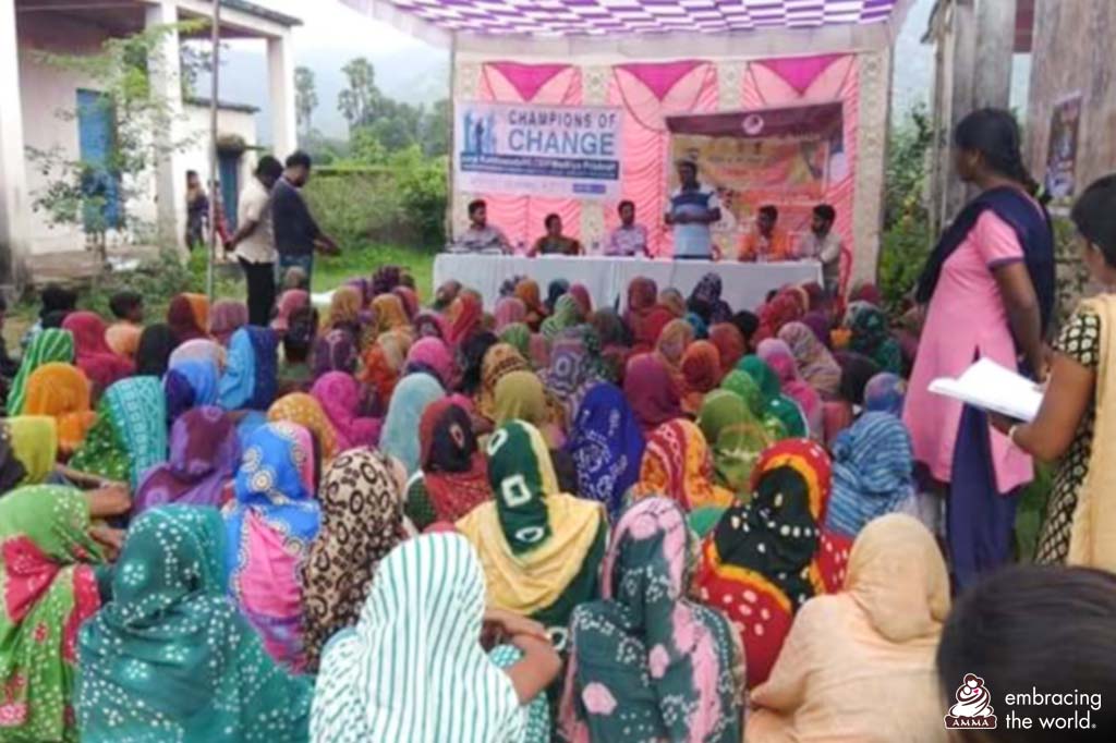 A large group of women sit and listen to a talk at an official gathering
