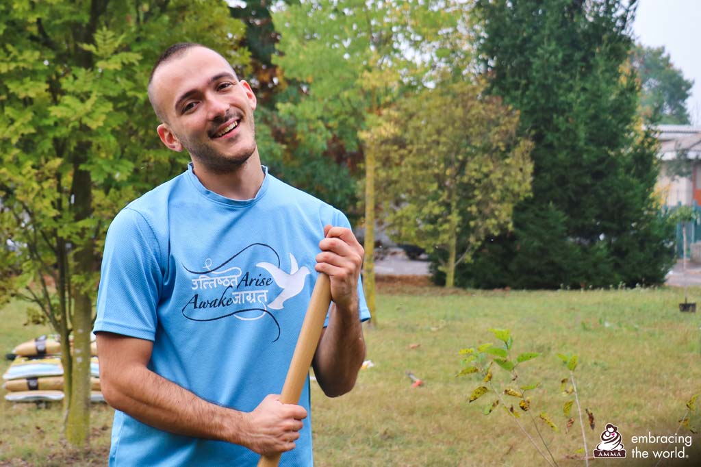 Robert holds a gardening tool and smiles into the camera