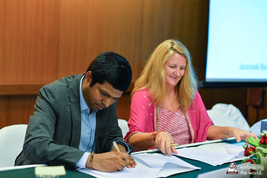 Amrita University staff signs document while smiling