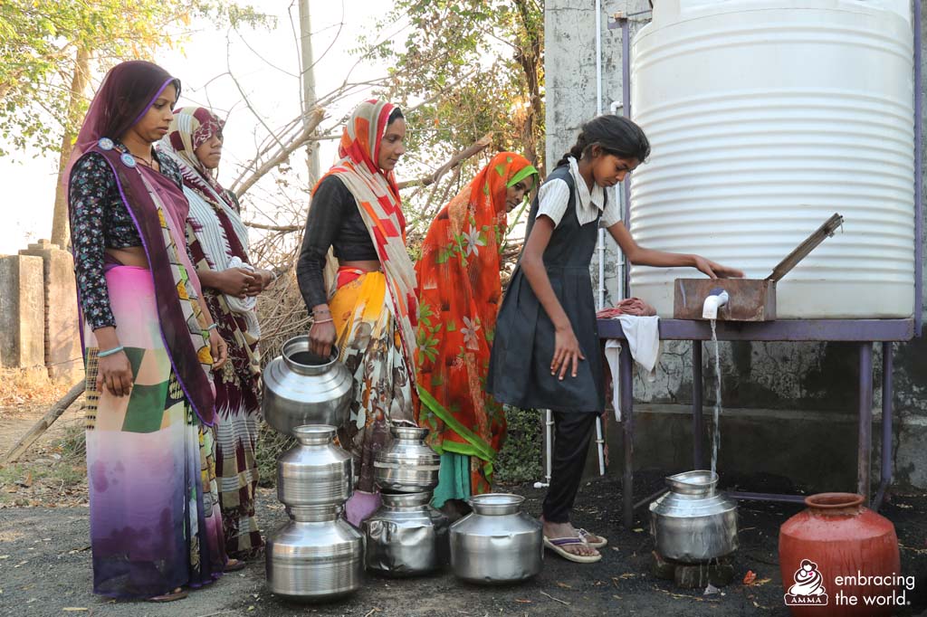 Women and children wait in line to fill up water containers