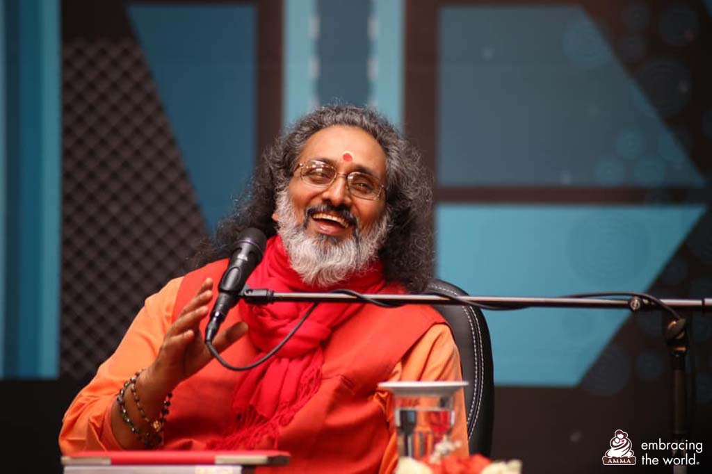 Swamiji laughs as he speaks into the microphone