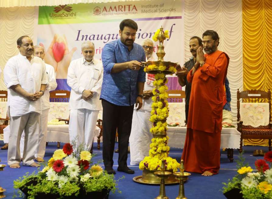 Mohanlal lighting a large lamp while Swami Turyamirtananda and others stand by