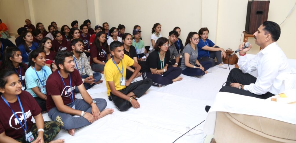 students seated on ground listening to a talk