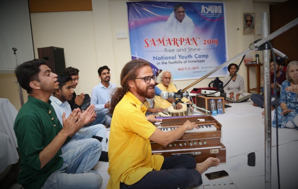 seated attendees playing various instruments such as tabla and harmonium