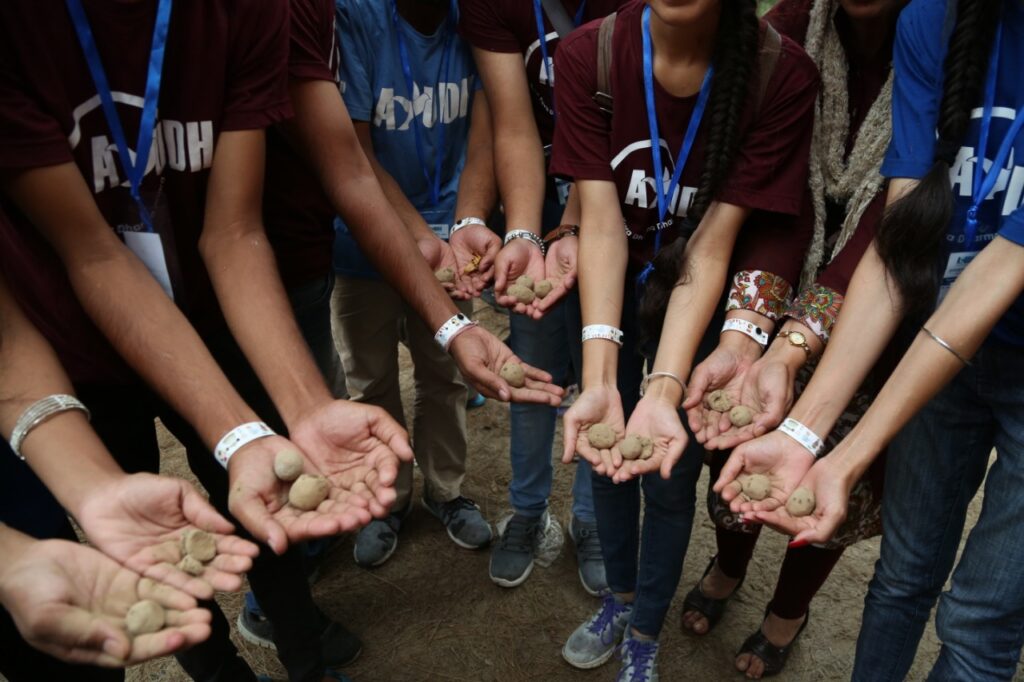 students holding out their hands each holding a seed ball