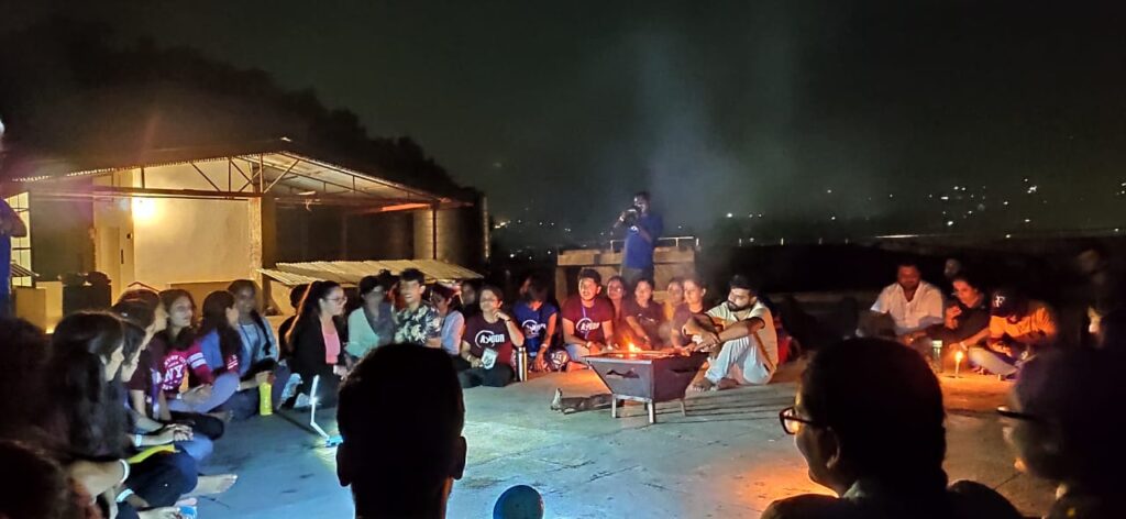 night scene of seated students singing playing harmonium