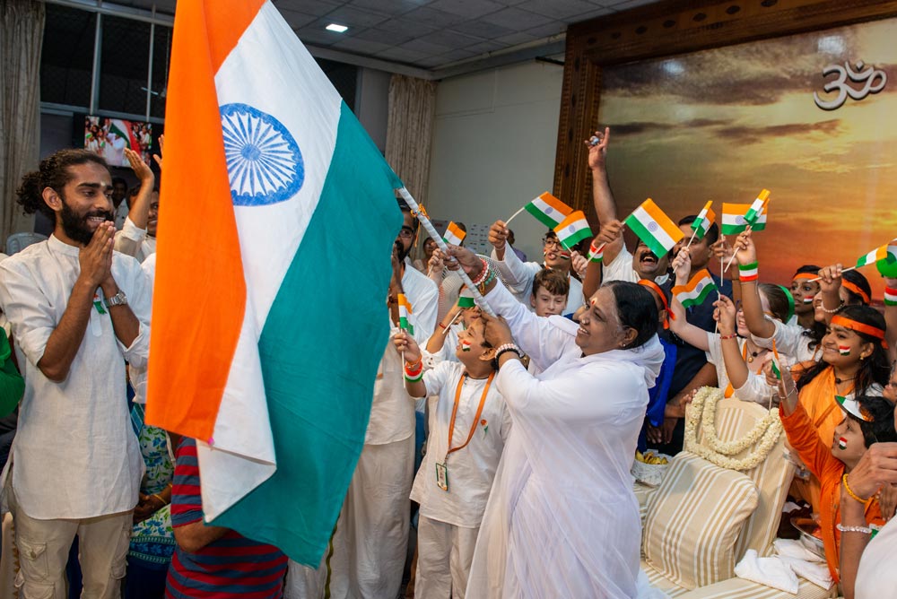 Amma holds the flag while surrounded by kids on the stage