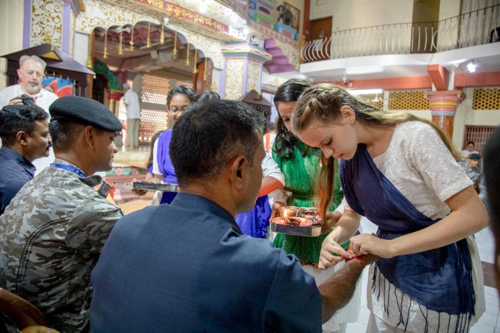 Tapasya, an ashram teenager, ties a bracelet around an officer's wrist