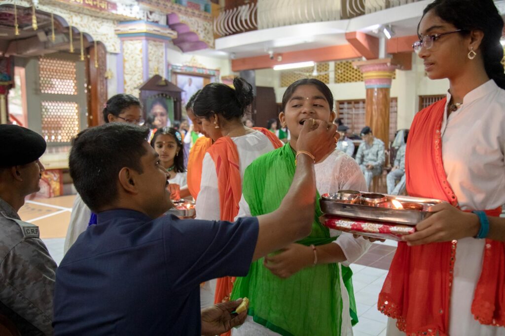 A CRPF officer feeds a sweet to an ashram child