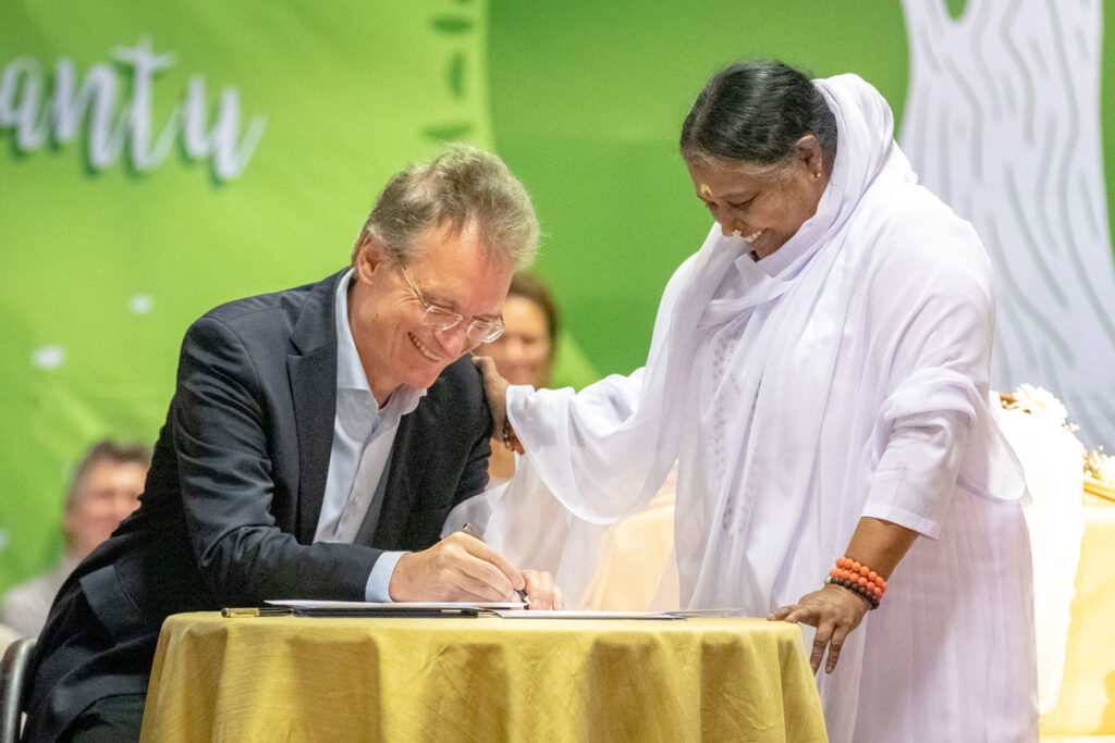  Prof. Joost Kok signs letter as Amma places her hand on his shoulder