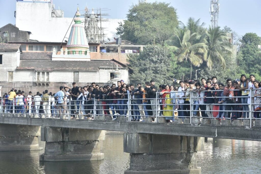 attendees looking down on the water while walking across a small bridge