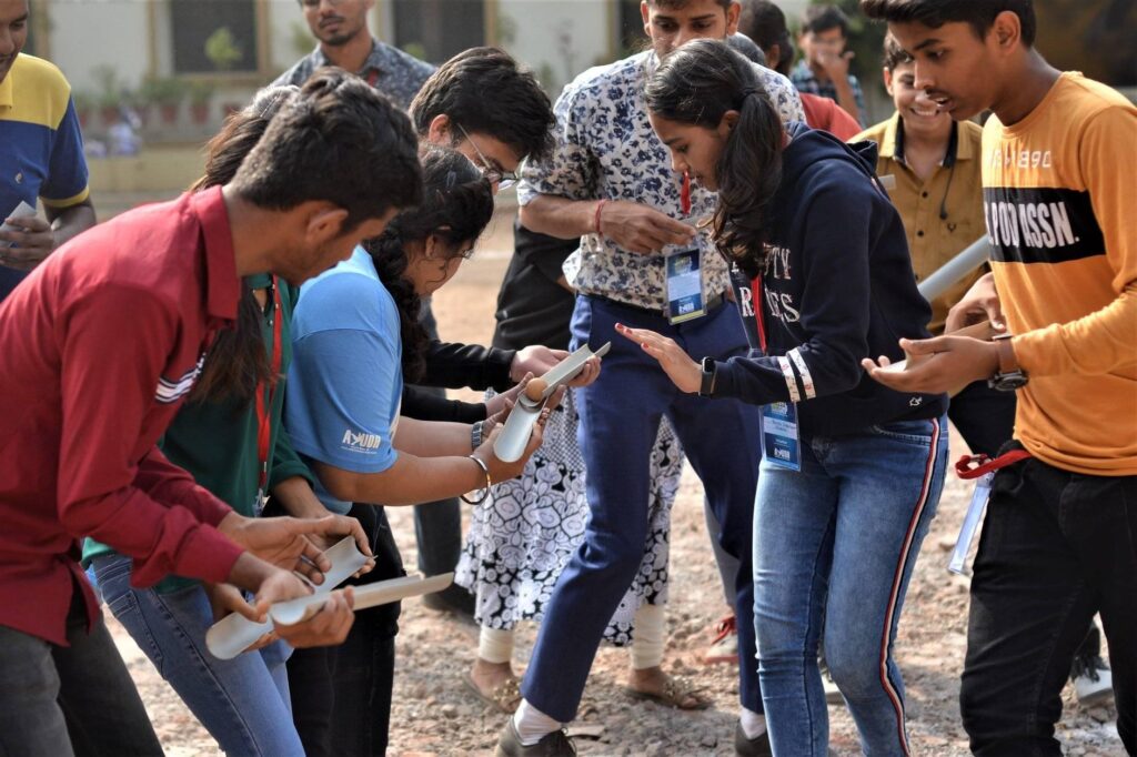 participants playing a game passing an egg to each other using the center tube from a roll of paper towel cut in half to form a trough