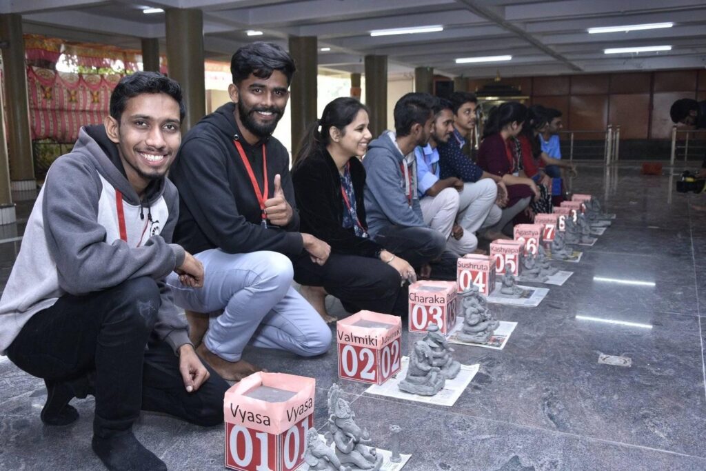 participants kneeling in front of small clay statues of Ganesh