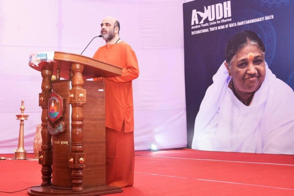 Swami Vidyamrita Puri standing on stage behind a dias talking.