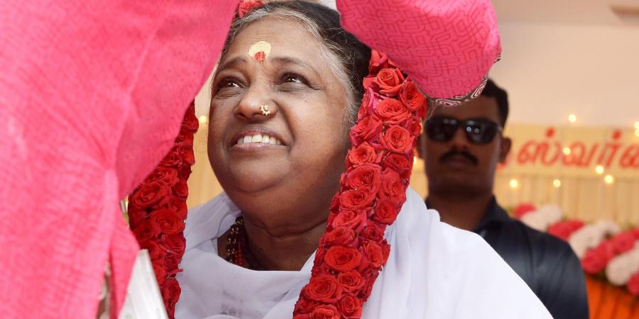 A red rose mala is placed on Amma's neck