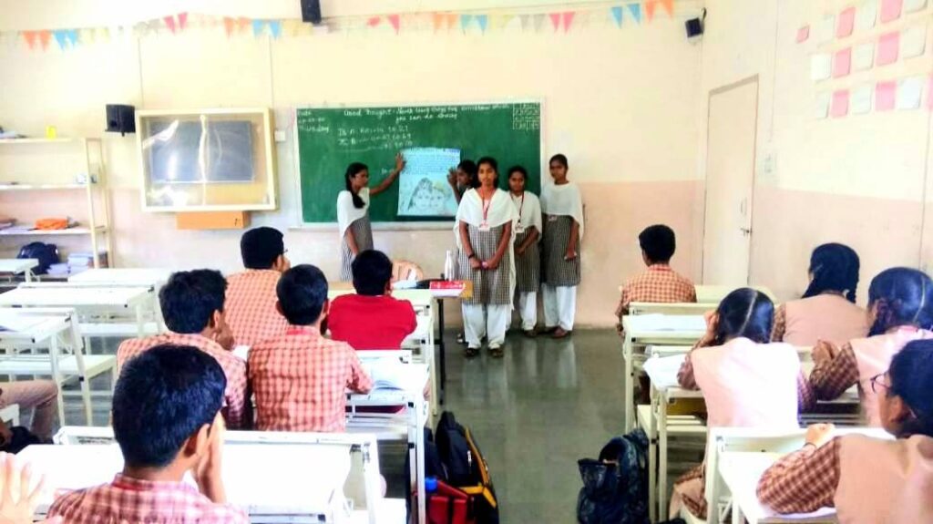 Amrita school students in their school uniforms seated at their desks listening to the AYUDH Shivaratri presentation.