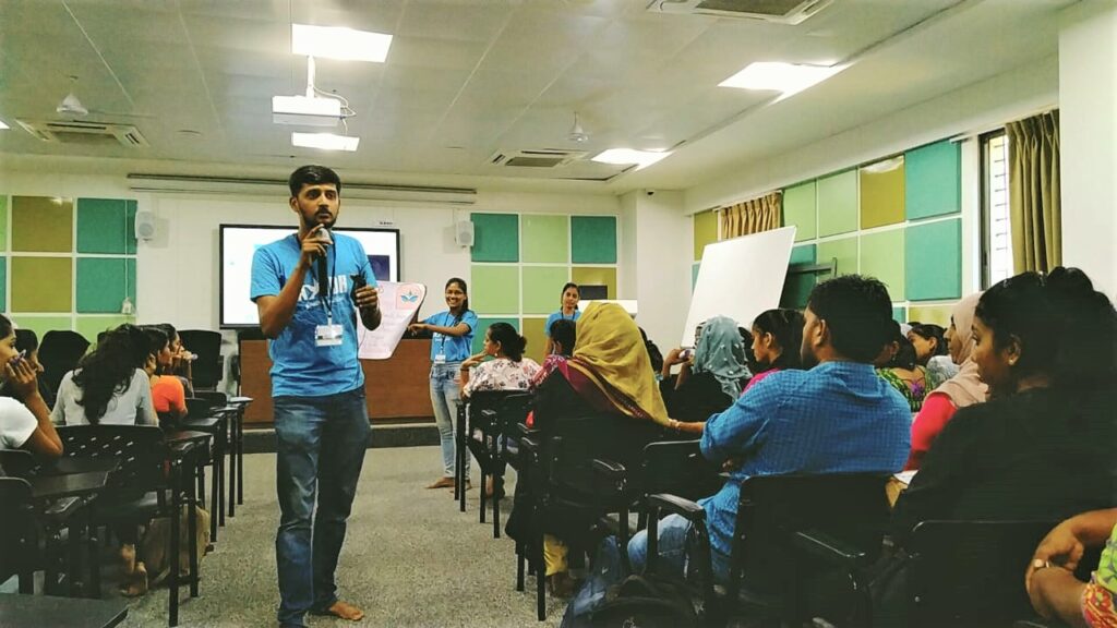 One AYUDh member walks with a microphone into the audience of college students.