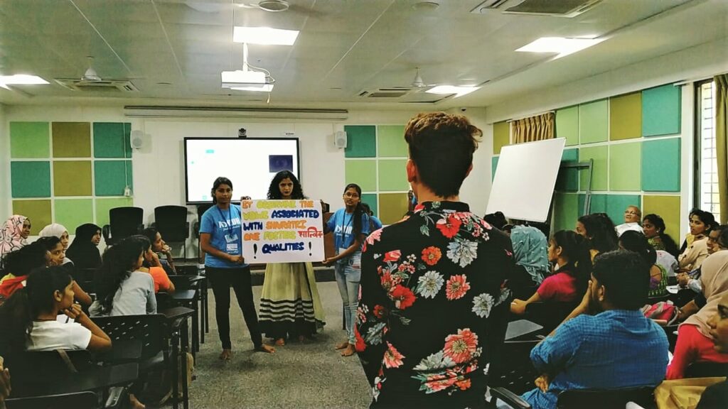 A college student with a bright flower patterned shirt on a black background asks a question to AYUDH.