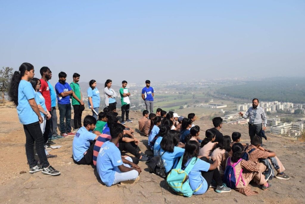 AYUDH members sit on a hill top listening to instructions and inspiration  for the Shiva temple clean up.