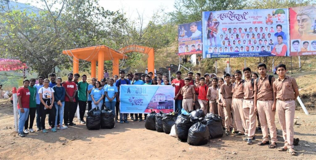 By the Shiva temple entrance, AYUDH members and Amrita school students in uniforms are gathered together with a banner and bags of garbage collected.