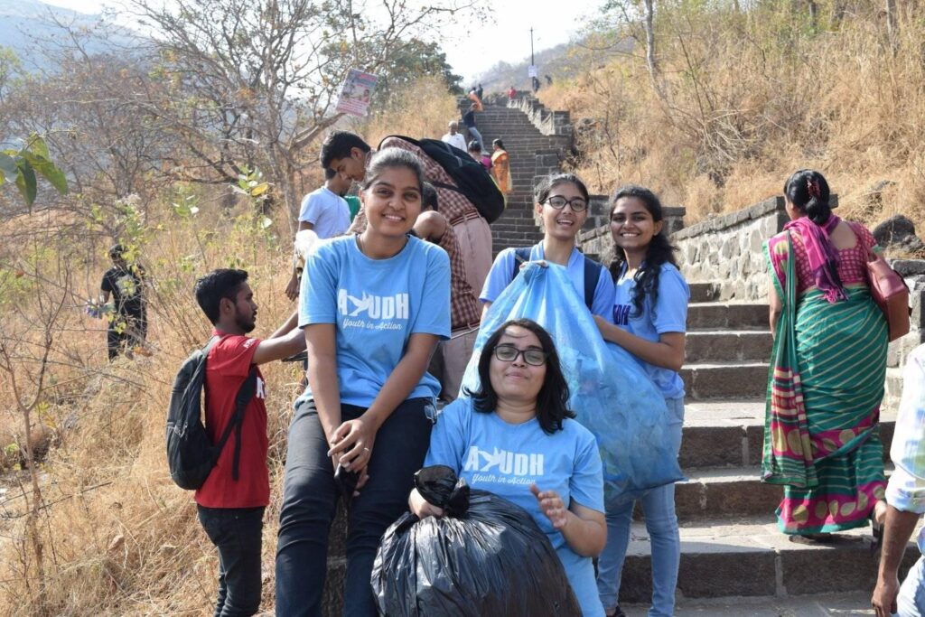 In light blue AYUDH t-shirts, bags of garbage are carried down the temple steps by young women.