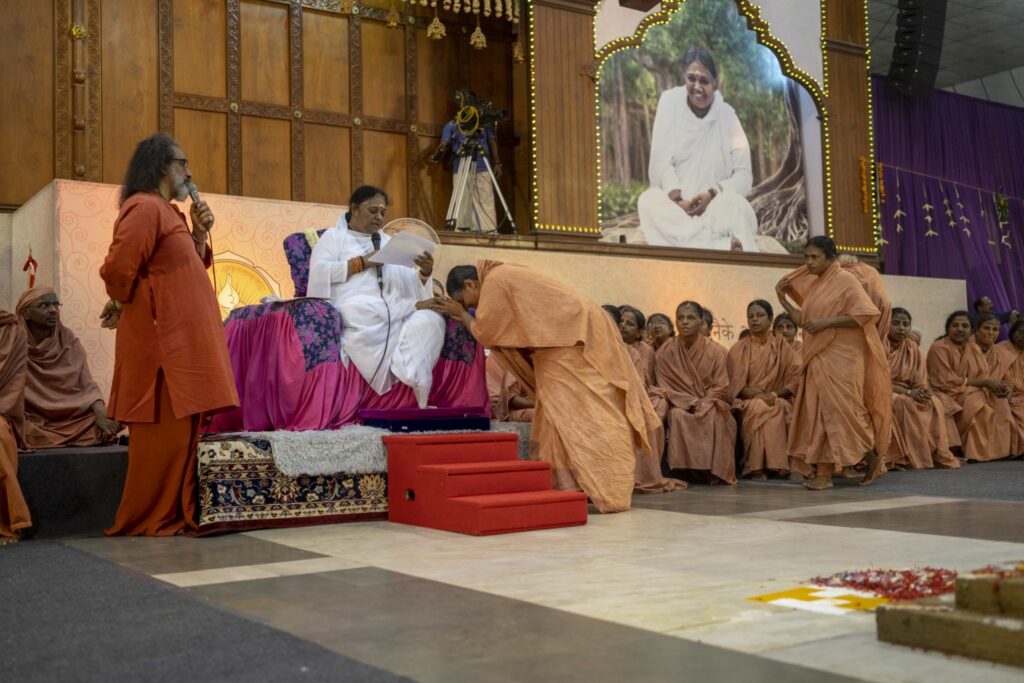 Seated, Amma speaks aloud each new female sannyasi name as the women each prostrate. 