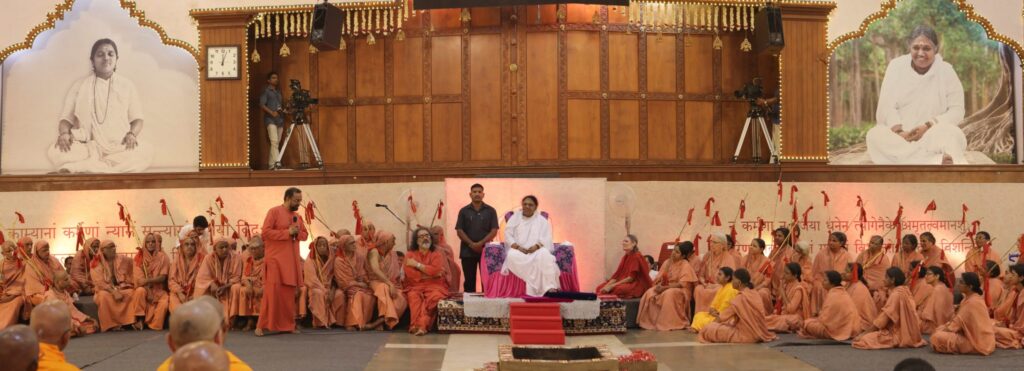 A wide view of Amma seated center with sannyasa male and female initiates on each side of her.