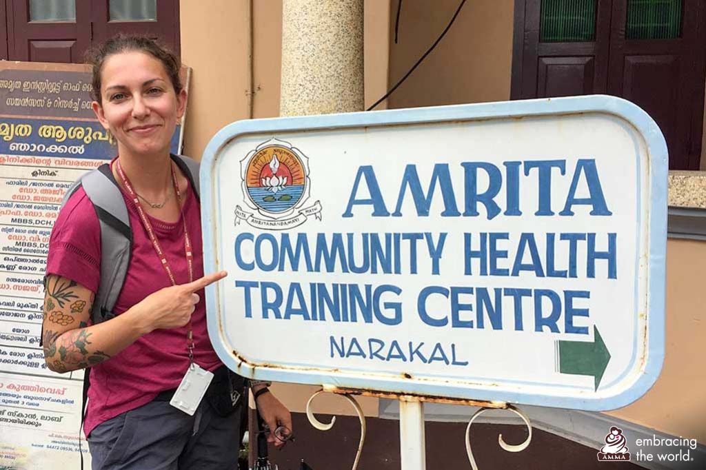 Woman from Canada points at a sign for the community health training centre