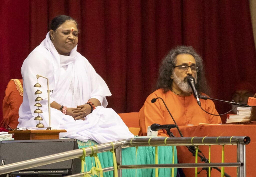 Amma sits while Swamiji speaks