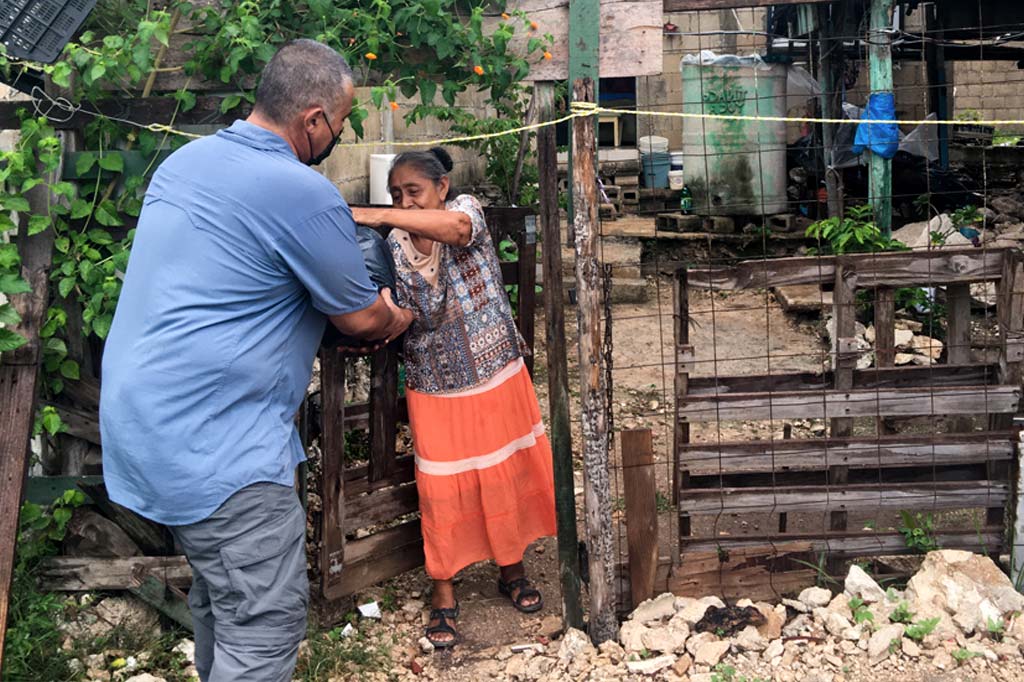 Mario Martinez hands a bag of grocery supplies to a woman in an impoverished neighborhood in Cancun