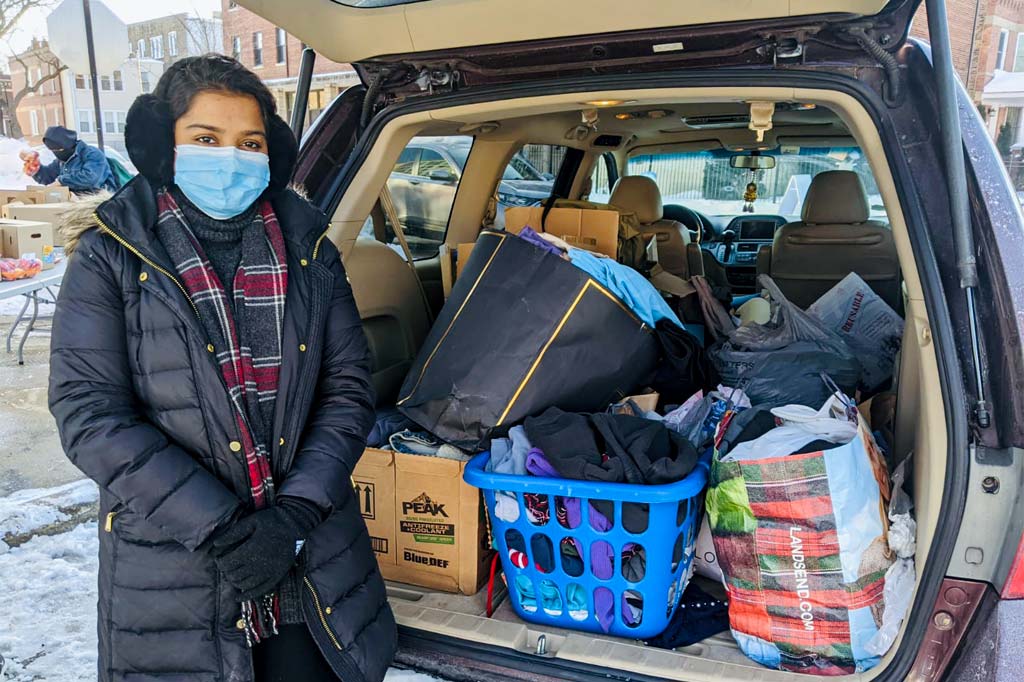 Volunteer stands in front of car filled with provisions