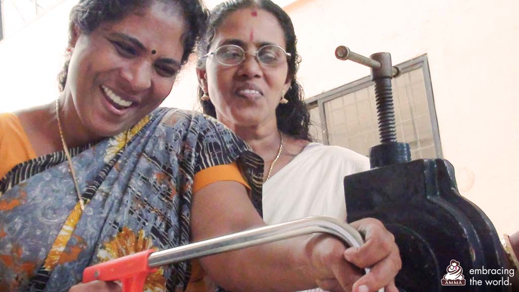 Two women smile while learning how to operate equipment.