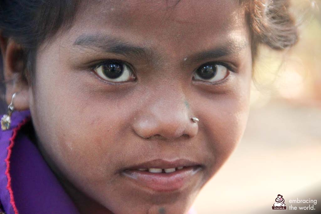 Close up on a small child's face. She looks seriously and directly at the camera. 