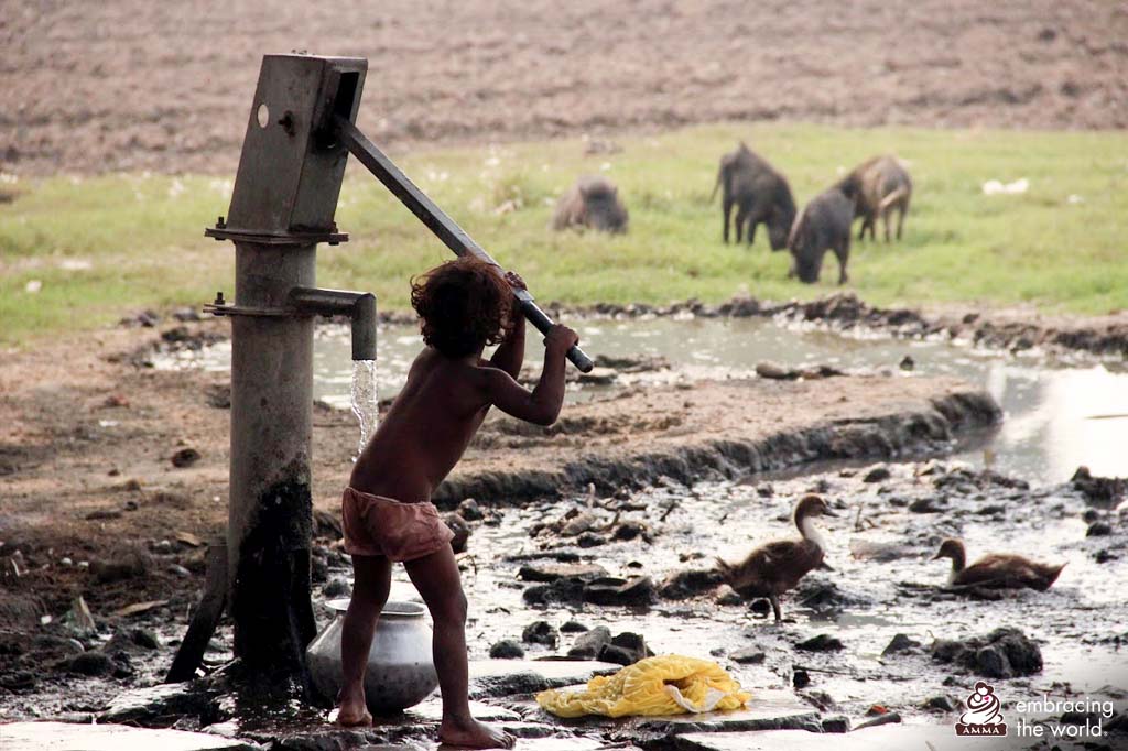 A small child tries to pump water alone near a stream