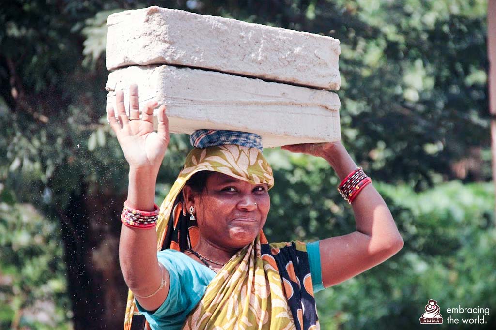 A woman balances bricks on her head