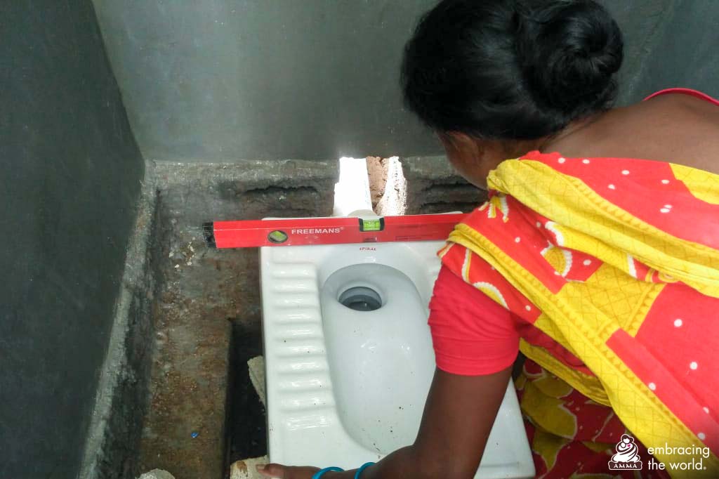 A woman is measuring a toilet as she installs it