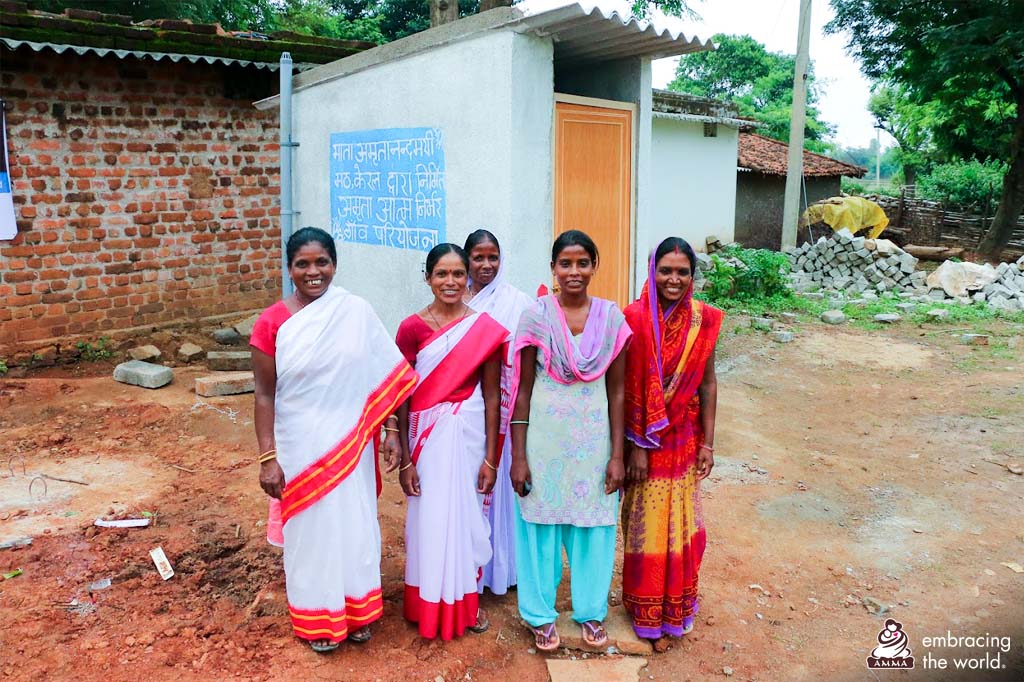 Five women stand and smile in front of a new toilet