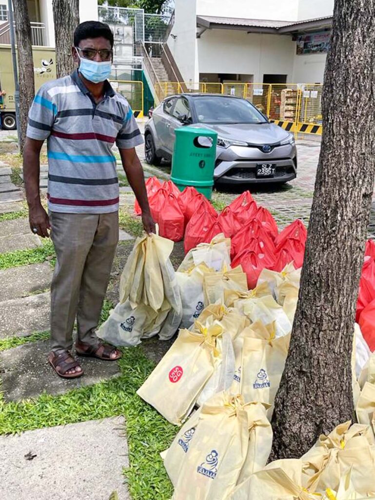 Man standing outside next to many carefully packed bags containing the dontations.