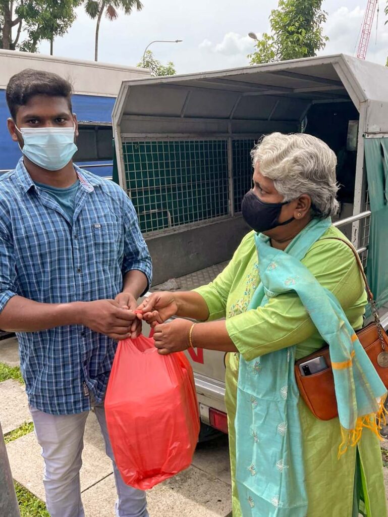 Lalitha Pillai handing a package of supplies to one of the dormitory coordinators.  