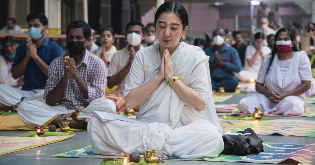Woman sits for the puja with hands folded in prayer