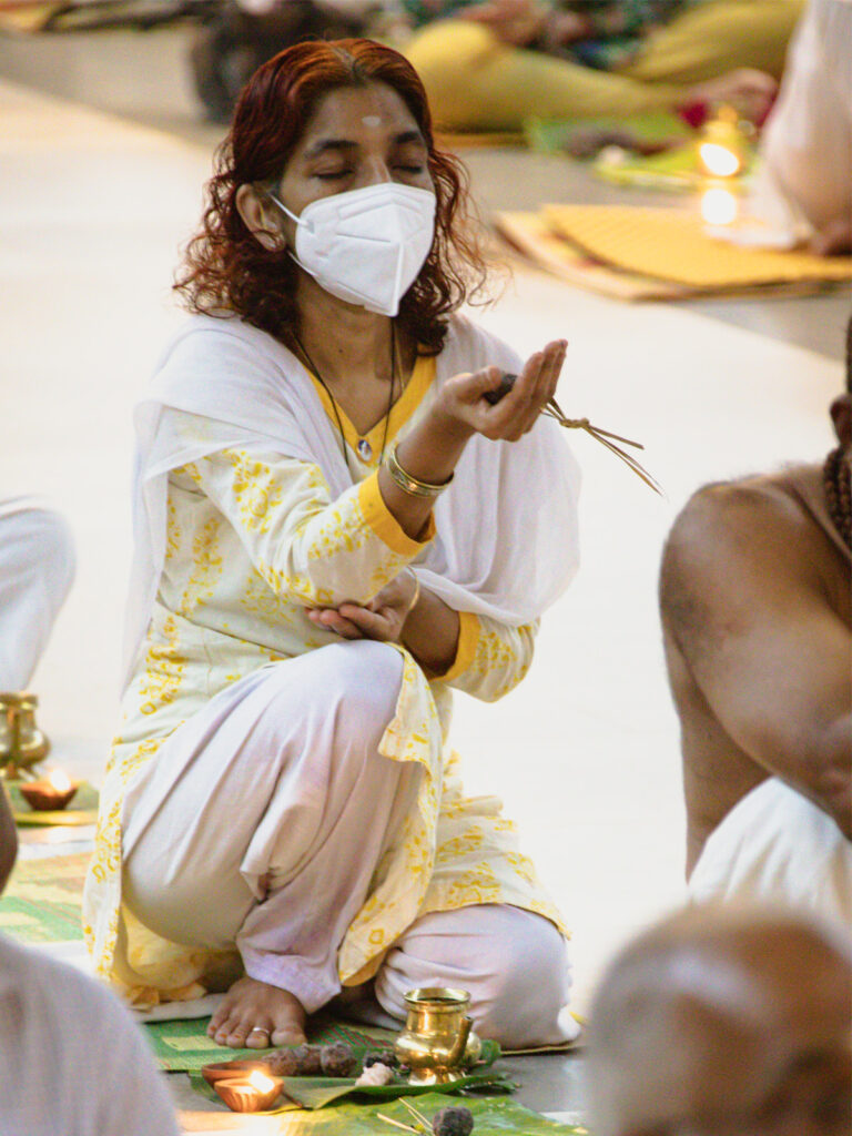 Woman holds up an offering as part of the puja